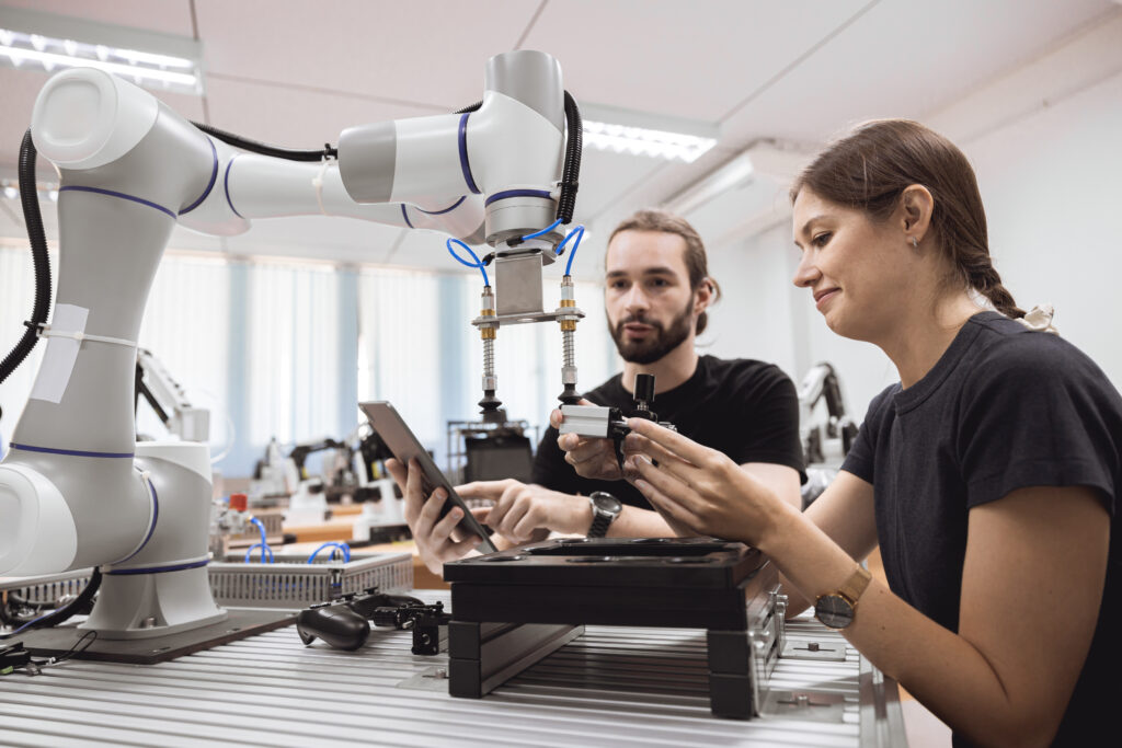 Engineers working with an industrial robotic arm to train and evaluate robotics AI systems